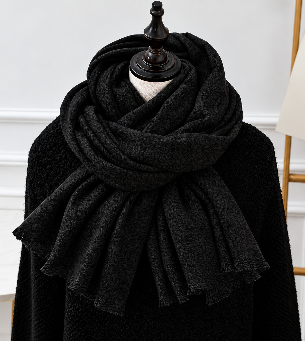 Black fringed scarf wrapped in generous folds on a mannequin dressed in a black knit jumper 3