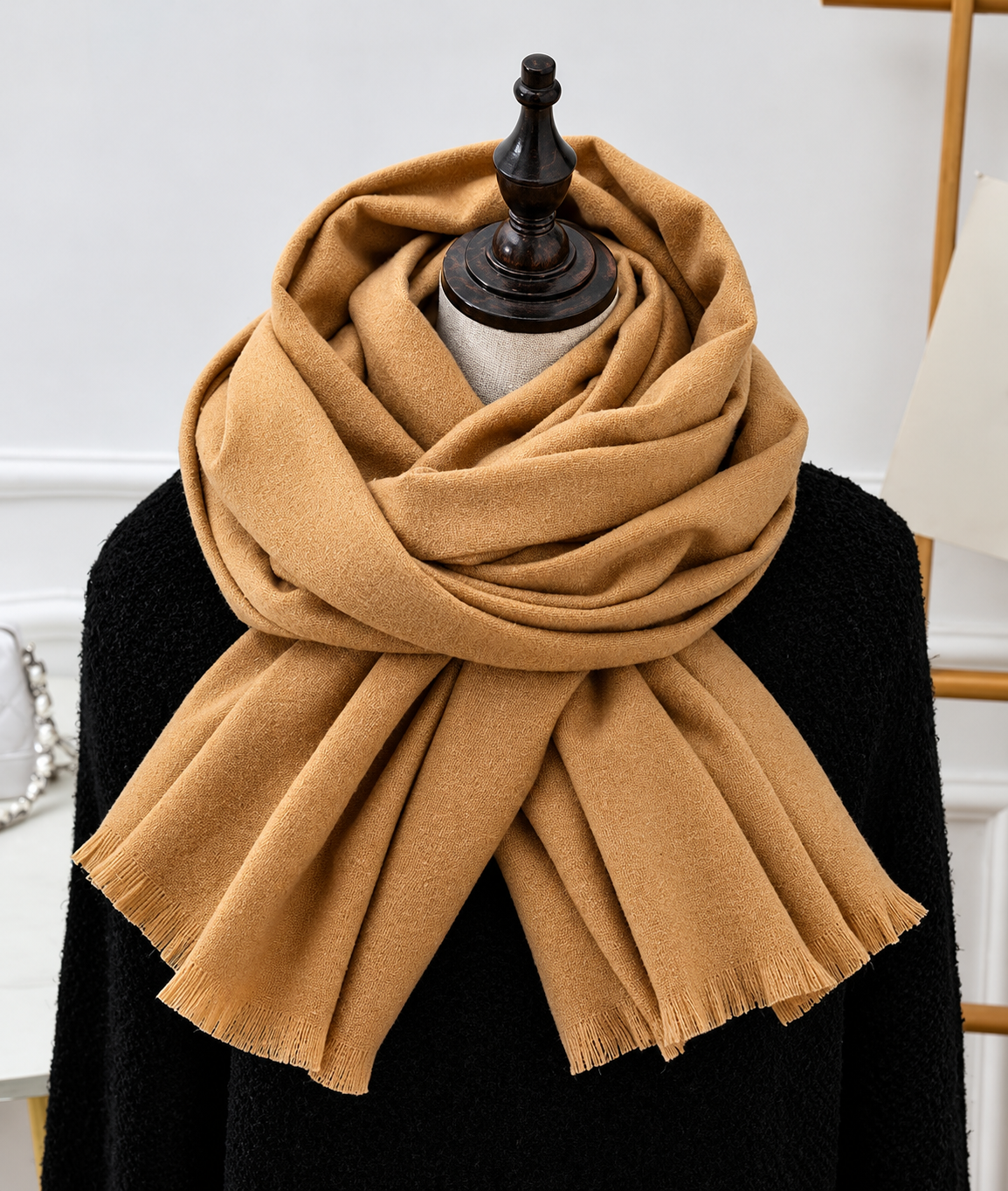 Mustard camel-toned fringed scarf layered around a mannequin wearing a black knit top 5