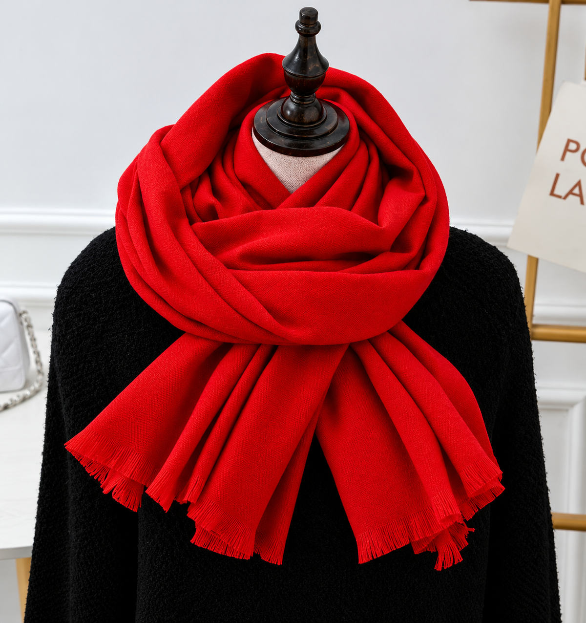 Bright red fringed scarf wrapped around a mannequin dressed in a black knit top 8