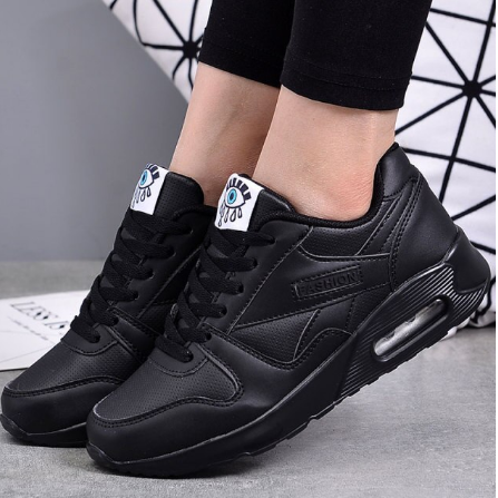 Worn view of all-black trainers with a visible air cushion heel and black laces 2