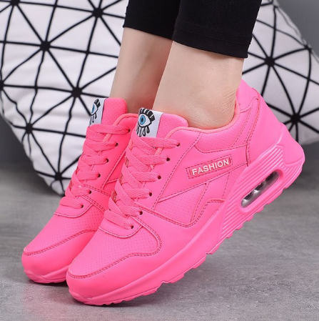 Worn view of bright neon pink trainers with an air cushion sole and pink laces 3