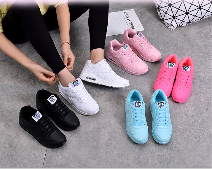 Black, white, pink, neon pink and light blue trainers laid out on the floor while a wearer laces one 4