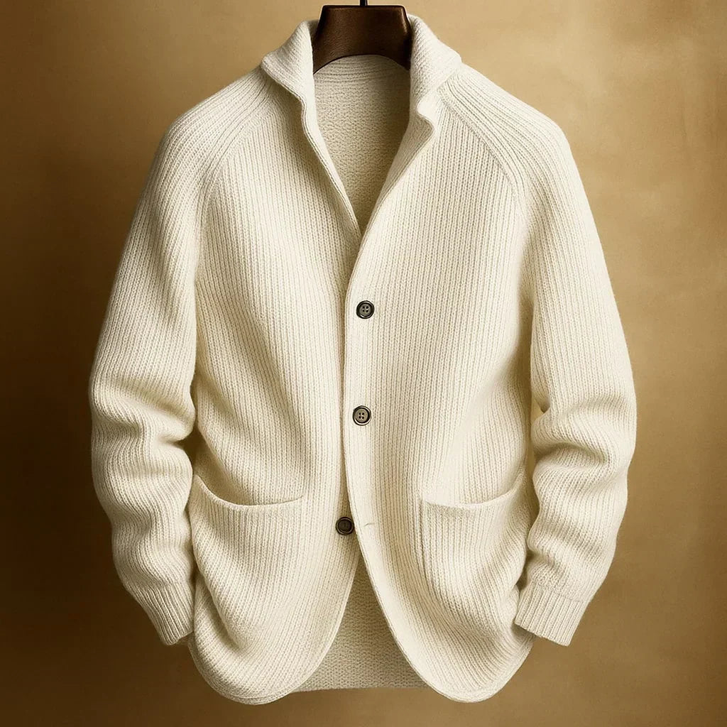 Cream ribbed knit cardigan with three buttons and patch pockets, hanging against a warm golden backdrop 2