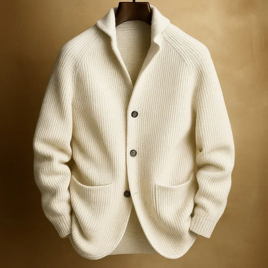 Cream ribbed knit cardigan with three buttons and patch pockets, hanging against a warm golden backdrop 2