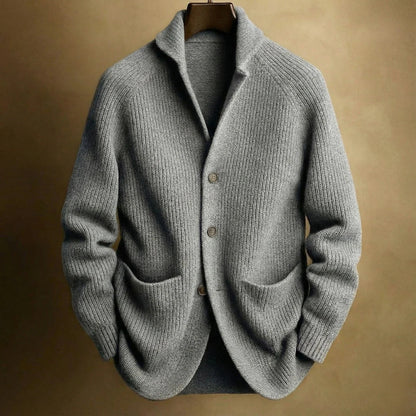 Grey ribbed knit cardigan with raglan sleeves and deep front pockets, hung against a golden-brown backdrop 5