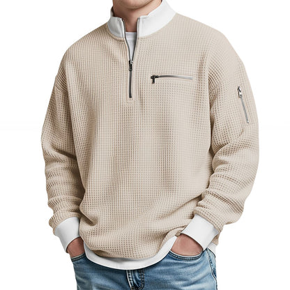 Front view of the beige waffle-knit jumper worn with jeans, with white contrast collar, ribbed cuffs and zipped chest pocket. 5