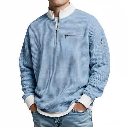 Front view of the light blue waffle-knit jumper worn with jeans, showing the white collar, chest zip pocket and sleeve zip pocket. 4