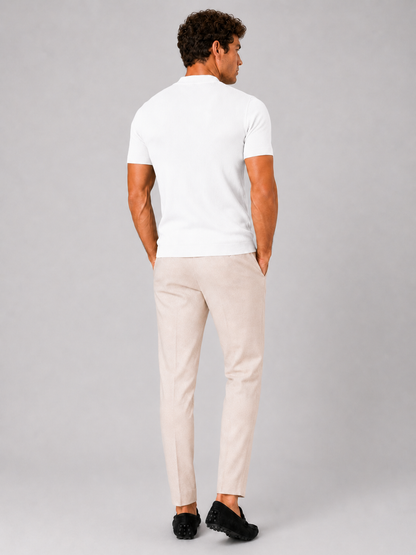 Back view of the white ribbed top worn with cream trousers and black loafers, model's hands in pockets. 14