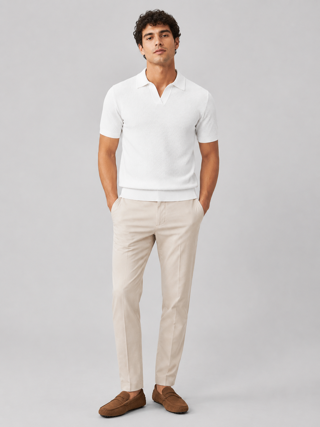 Full-length studio view of model in white knit polo, light beige trousers and tan suede driving loafers 32