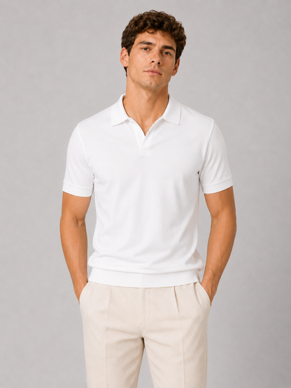 Model in a white short-sleeved polo with an open collar, seen from the front in a close studio shot, worn with cream trousers. 1