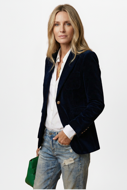 Three-quarter view of the navy velvet blazer on a model, one hand in her jeans pocket 3
