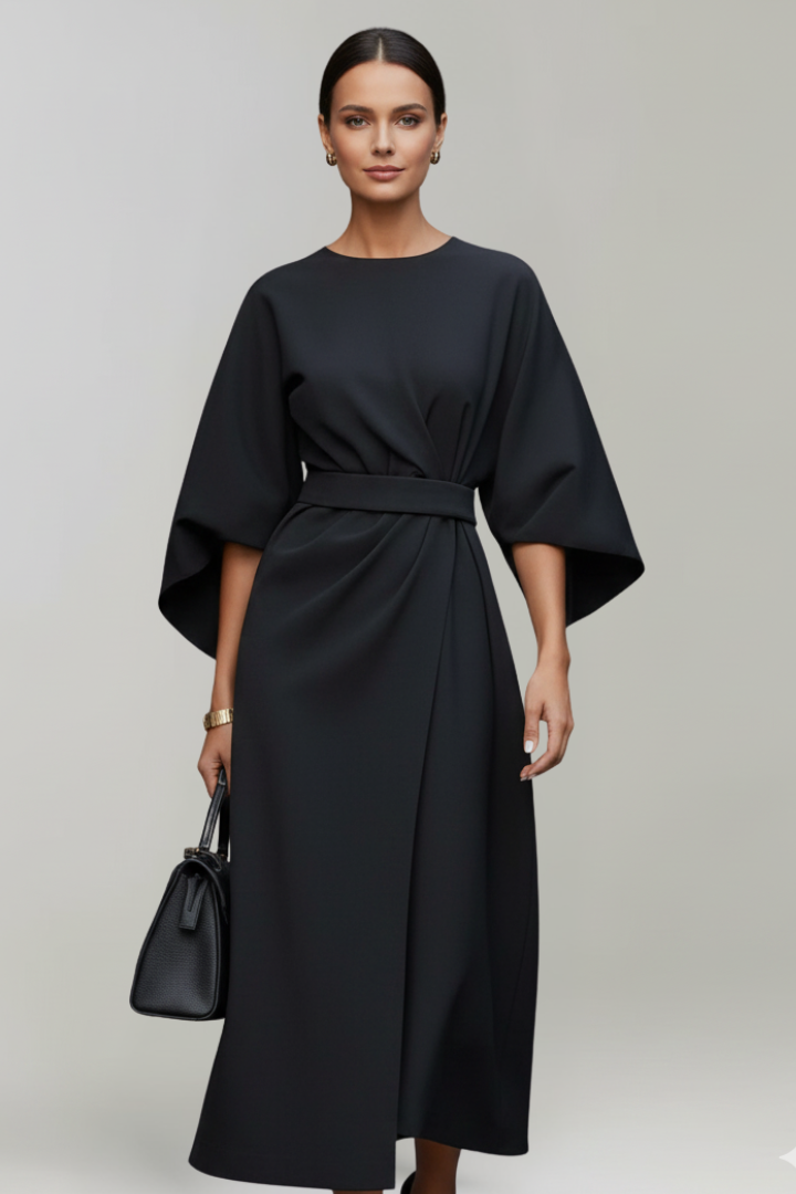 Model wearing the dress in black, front view, carrying a black handbag 7