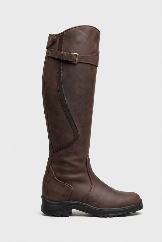 Side view of a dark brown leather knee-high boot with brass buckle strap and black lug sole 1