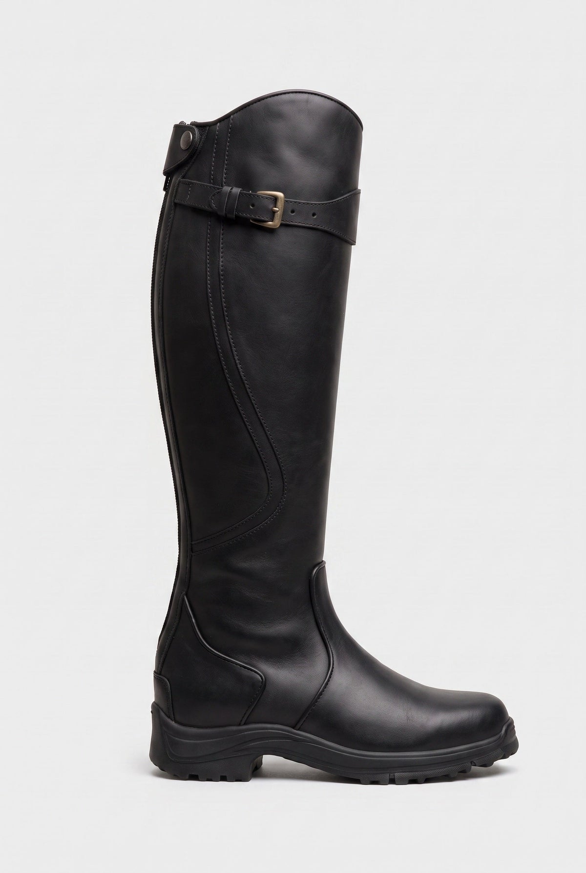 Side view of the knee-high boot in smooth black leather with brass buckle strap and chunky black sole 3