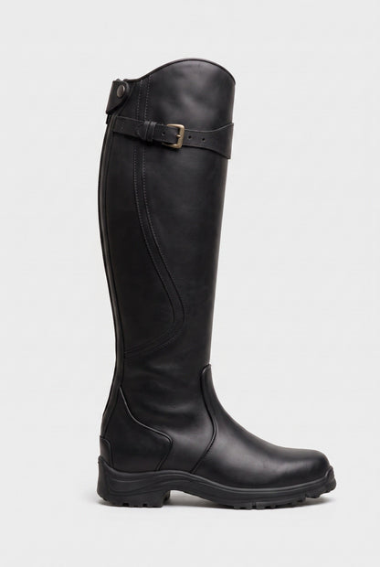 Side view of the knee-high boot in smooth black leather with brass buckle strap and chunky black sole 3