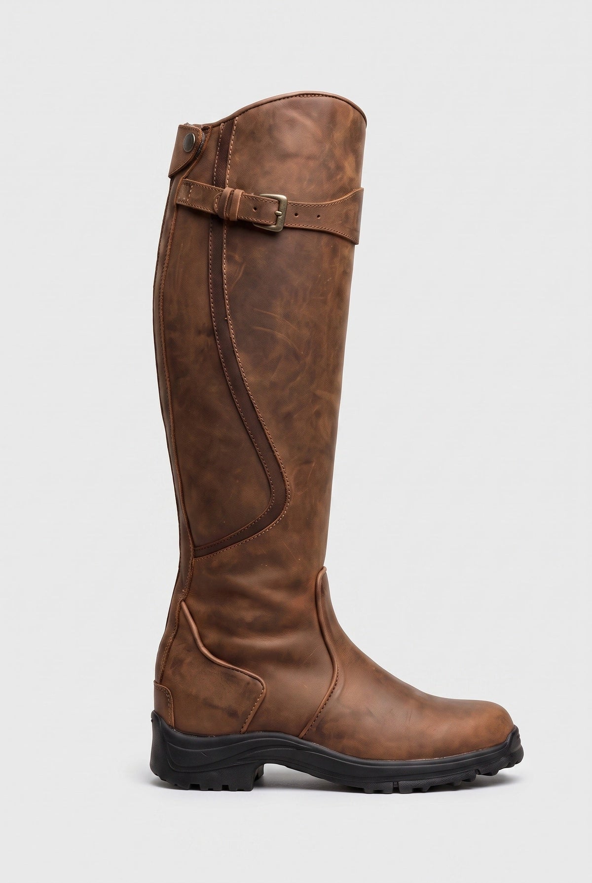 Side view of the knee-high boot in tan brown distressed leather with brass buckle and black lug sole 4