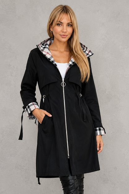 Model wearing the black version of the hooded coat, with a ring-pull zip and checked lining at hood and cuffs. 3