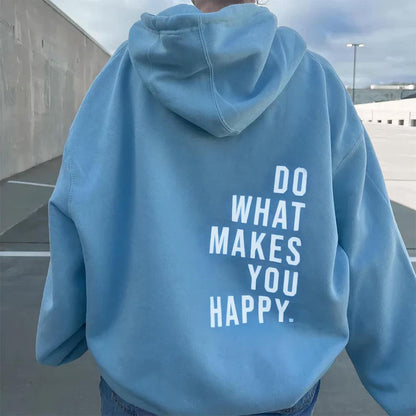Back view of a light blue hoodie worn outdoors, with a white slogan stacked in capital letters across the lower back. 2