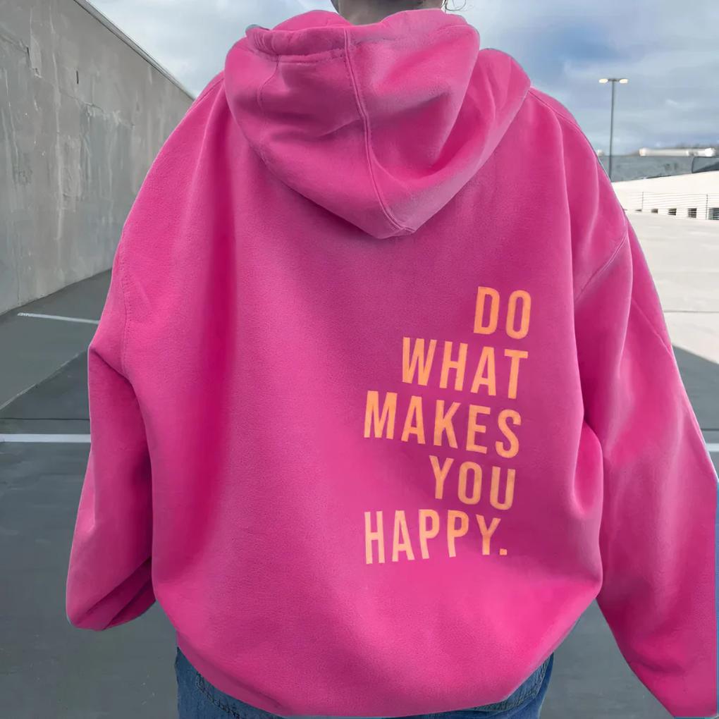 Back view of a bright pink hoodie worn outdoors, with an orange slogan printed in stacked capitals on the lower back. 3