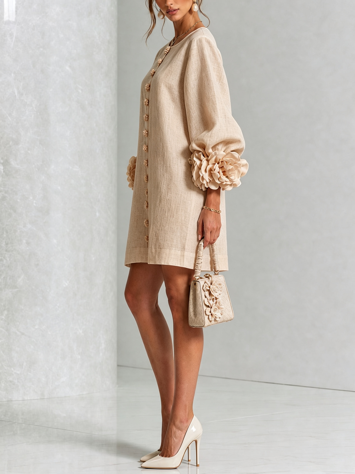 Side view of the beige dress, showing the straight shape, flower buttons down the front and large rose cuffs. 24