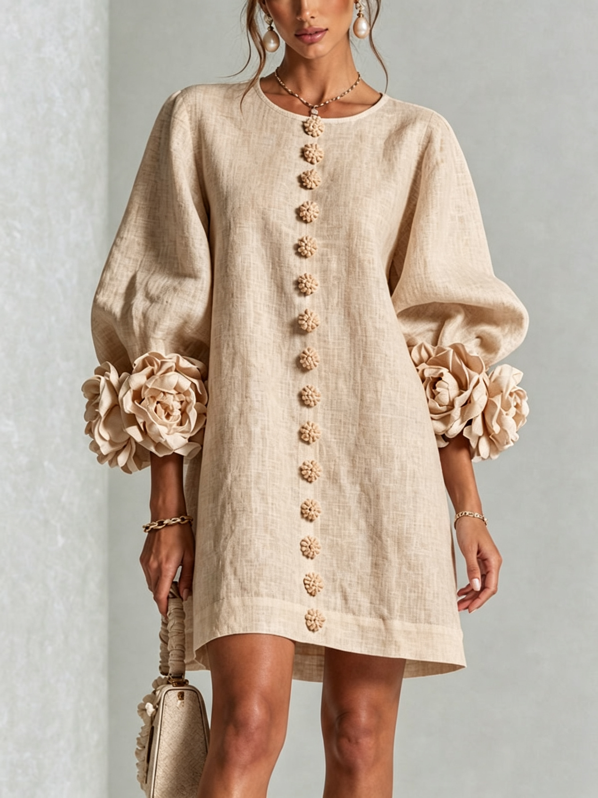 Close front view of the beige linen dress, with a line of knotted flower buttons and rose cuffs on puffed sleeves. 23