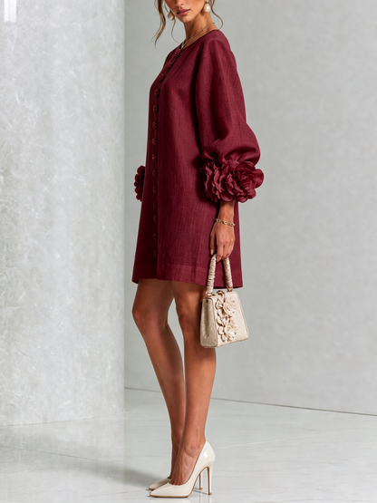 Side view of the burgundy mini dress on a model, showing the puffed sleeve with a ruffled flower cuff and a cream handbag. 36