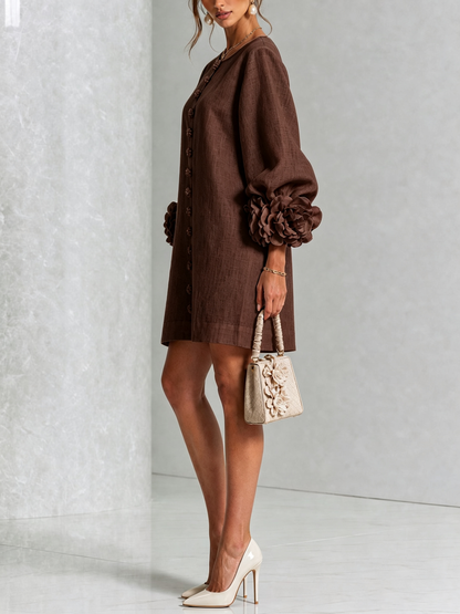 Side view of the dark brown dress, showing the loose straight fit, flower buttons and ruffled floral sleeve cuffs. 28