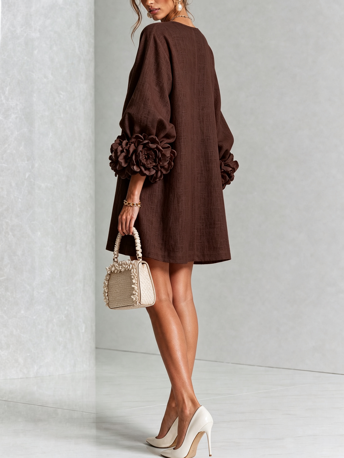 Brown dress from the back on a model looking over her shoulder, with a plain back and large rosette sleeve trim. 33