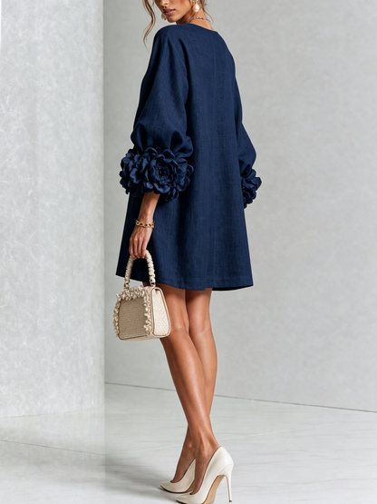 Back view of the navy dress on a model, with a loose plain back and large petal-style cuffs. 13