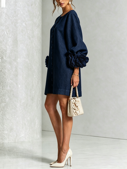 Side view of the navy dress on a model, showing the balloon sleeve, floral cuff and a cream handbag. 12