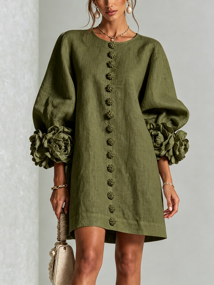 Studio shot of the olive green version with the front flower buttons, balloon sleeves and large rosette cuffs, model holding a handbag. 11
