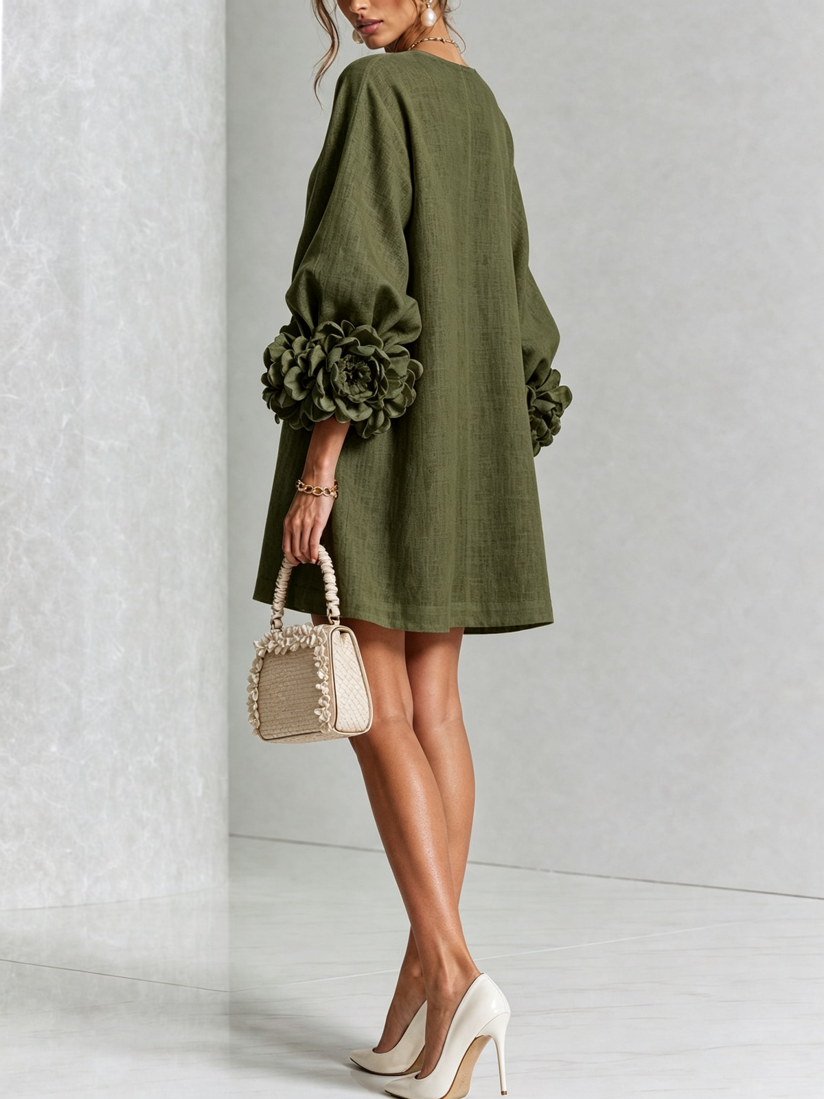 Back three-quarter view of the olive green dress, showing the plain back, loose shape and rose-trimmed sleeve cuffs. 9