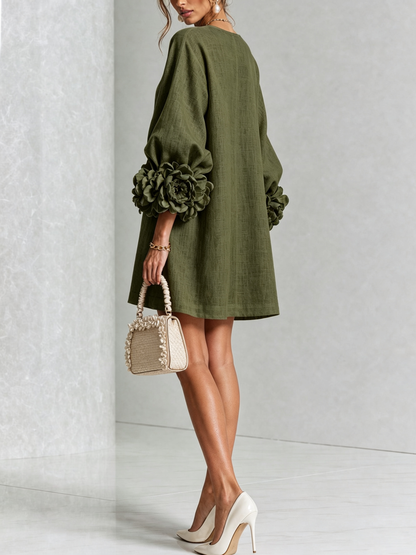 Back view of the olive green dress on a model, showing the plain back and the large flower-shaped cuffs. 9