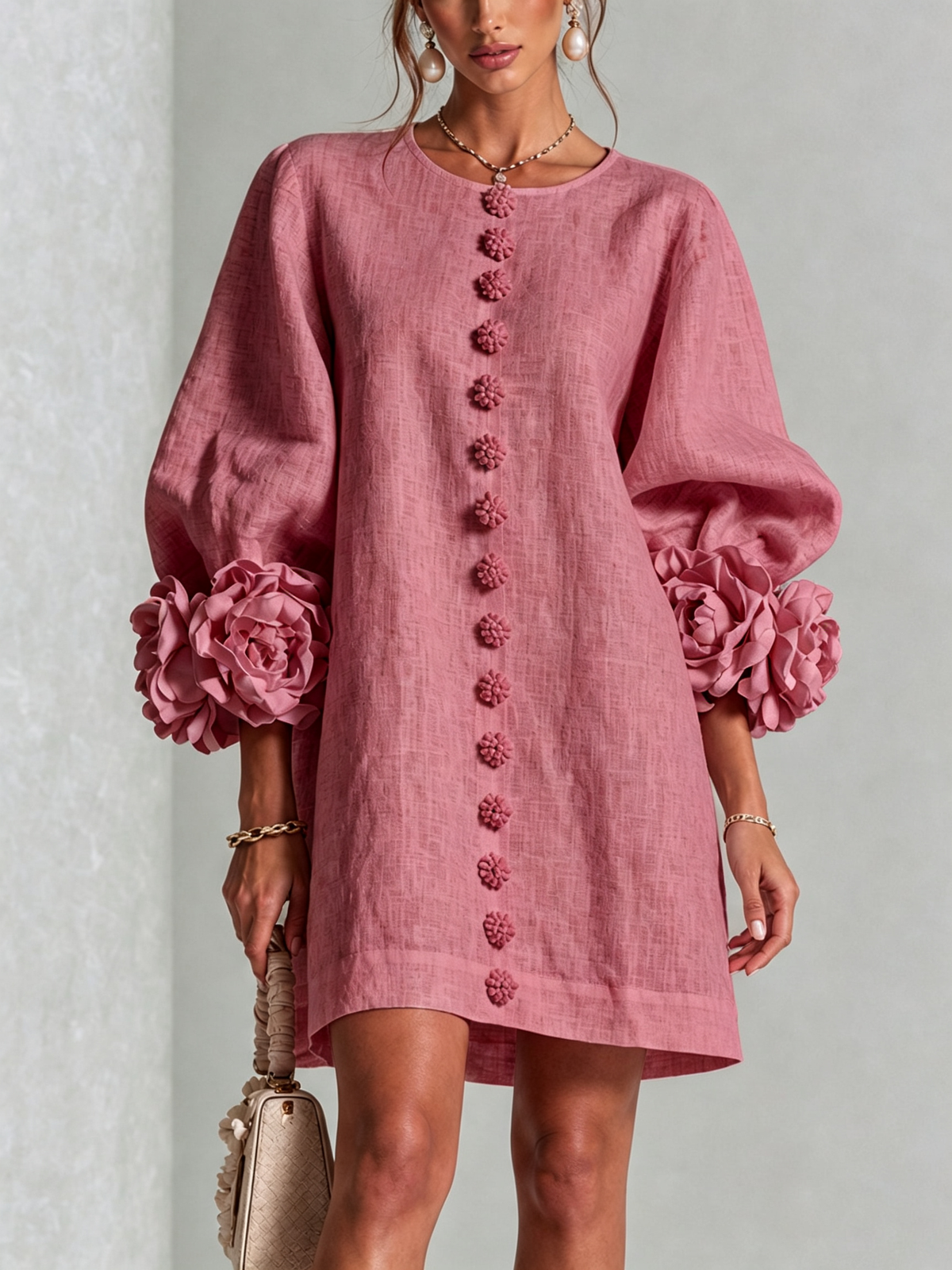 Front view of the dusky pink version on a model, showing the flower-shaped buttons down the centre and rosette sleeve trim. 44