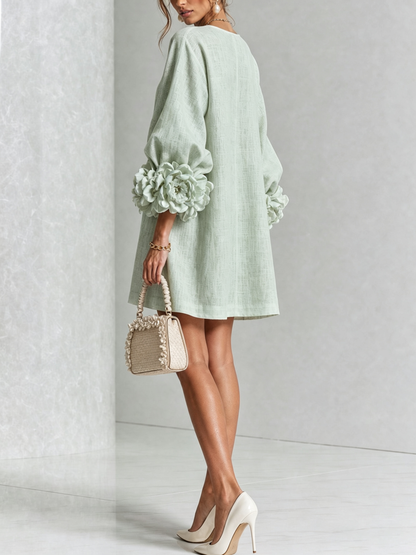Back view of the mint green mini dress, showing the loose plain back and large flower-style cuffs, with cream heels. 33