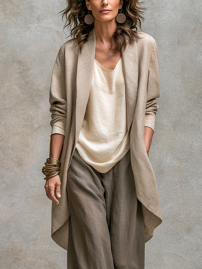 Close-up of the open long beige jacket with its wide shawl collar and curved hem, layered over the cream top. 3