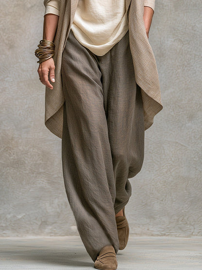 Detail of the relaxed wide-leg taupe trousers in a textured linen-look fabric, with the jacket hem and cream top visible above. 5
