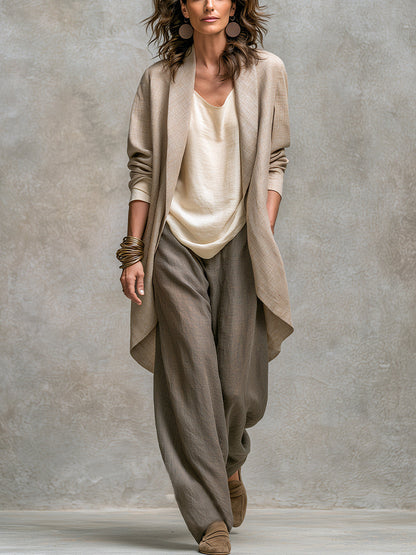 Full-length studio shot of a model wearing the open beige linen-look jacket over a cream top and wide-leg taupe trousers. 1