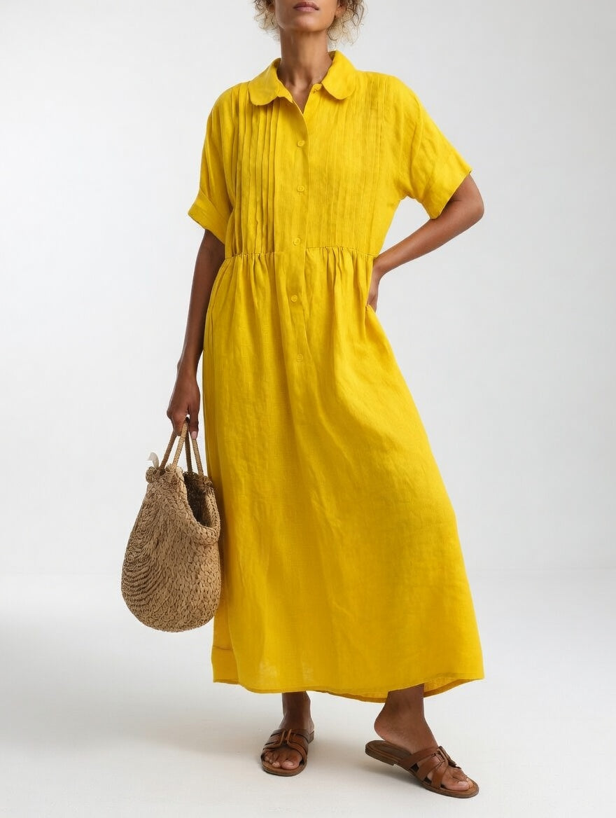 Model in the yellow dress with a hand on her hip, holding a straw tote, showing the loose, gathered skirt. 6