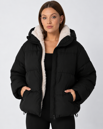 Front view of a model in a black puffer jacket worn open, with a cream fleece lining and hands in the pockets 11