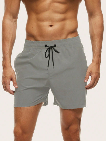 Front view on a model of light grey swim shorts with a black drawstring and eyelets. 11
