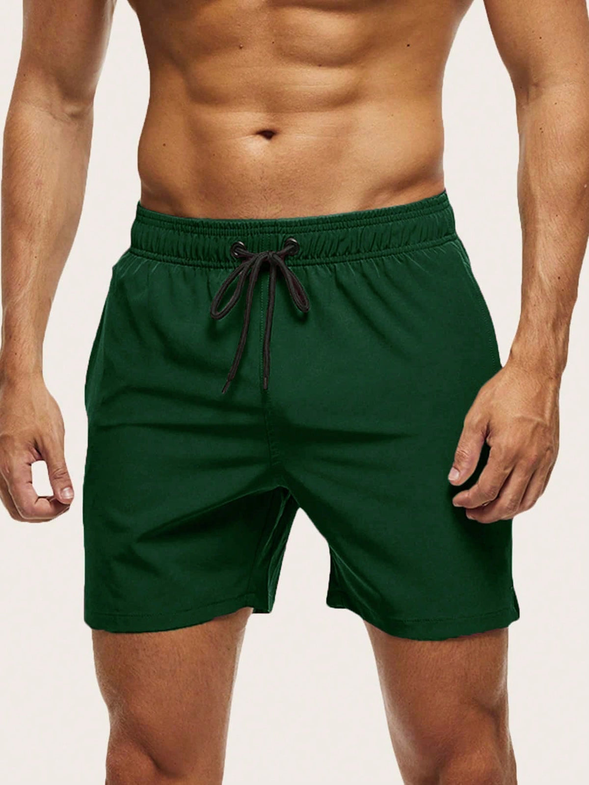 Front view on a model of dark green swim shorts with elasticated waist and black drawstring. 9