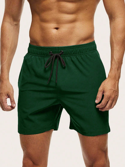 Front view on a model of dark green swim shorts with elasticated waist and black drawstring. 9