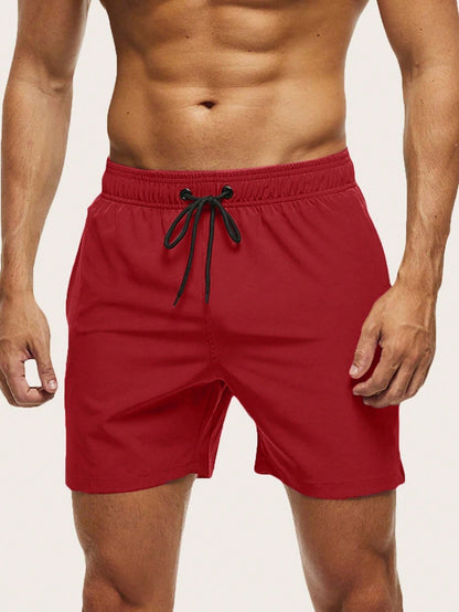 Front view on a model of red swim shorts with an elasticated waist and black drawstring. 1