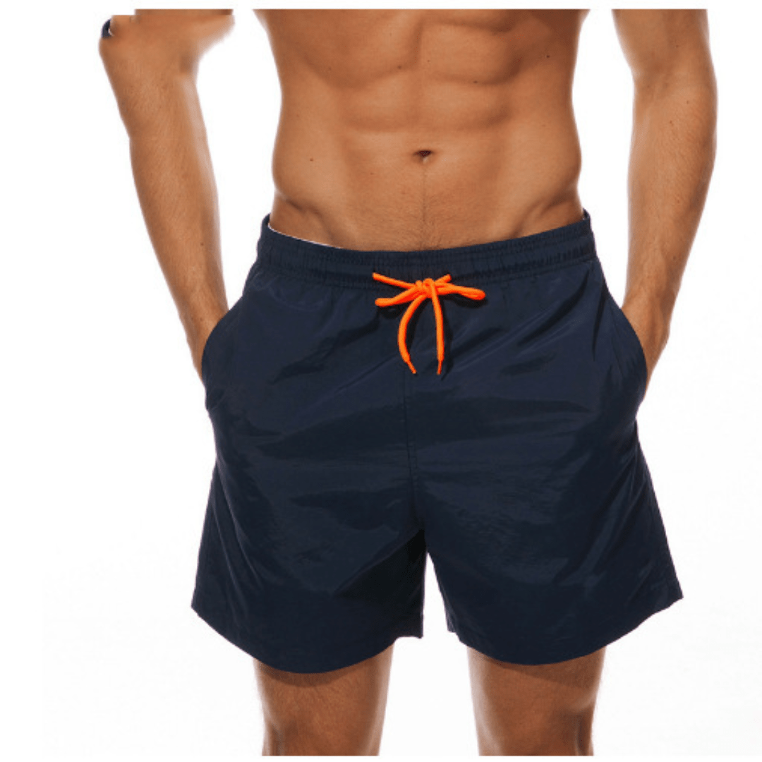 Front view of navy swim trunks with an orange drawstring, worn with both hands tucked into the pockets. 7
