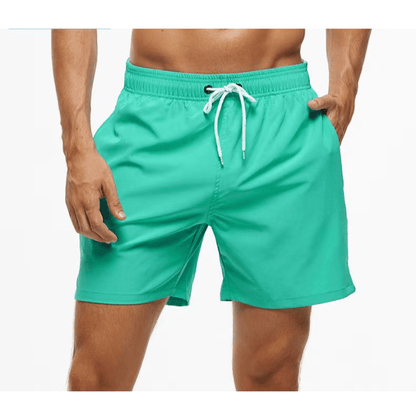 Mint green swim trunks with a white drawstring and elasticated waistband, worn by a model with one hand in a pocket. 8