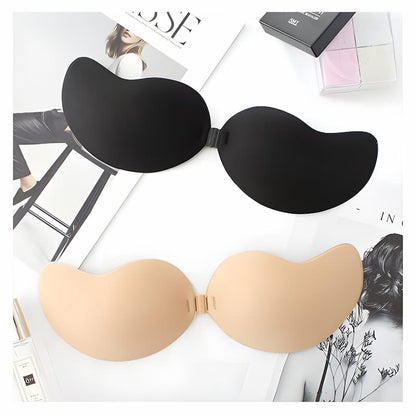 Flat lay of the black and beige adhesive bras with clasps joined, resting on magazine pages beside cosmetics. 9