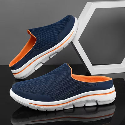 Pair of navy mesh slip-on mules with orange lining and sole stripe, one propped against a white hexagon frame. 3