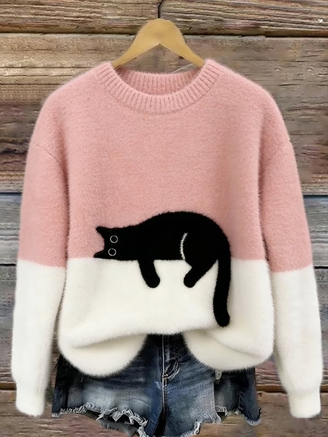 Pink and white fluffy jumper with black cat motif, hanging on a wooden background 3