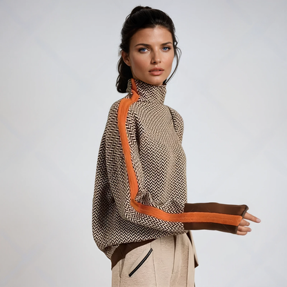 Model in profile against a plain backdrop wears the brown and cream herringbone jumper with orange side stripe, brown cuffs and beige trousers. 1